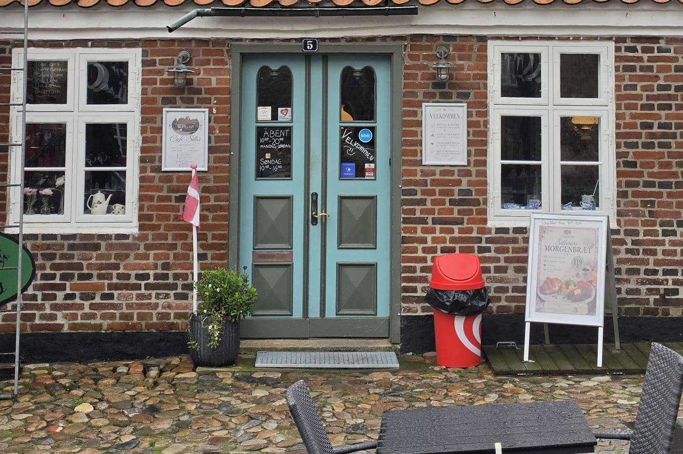 Den blå dobbeltdør i Torvet 5 med hvide sprossede vinduer på hver side og brosten foran